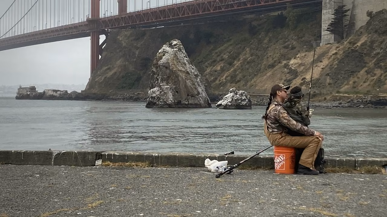 Ivan seated by the bay in early morning fog with the Golden Gate Bridge beyond.